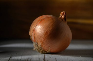 Issız bir soğan desenli derisini ve sıcacık renklerini sergiliyor. Kırsal bir ahşap zemine hafifçe vuruyor..