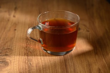 A glass cup filled with aromatic herbal tea glistens softly under natural light, inviting a moment of calm. clipart