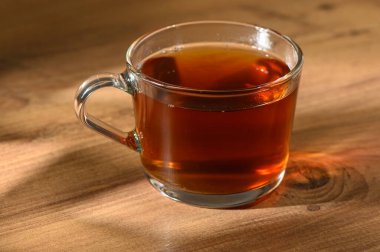 Buharı tüten bir fincan bitki çayı sıcaklığı ve rahatlığı yayar, dingin güzelliği ahşap bir yüzeye yerleştirir..