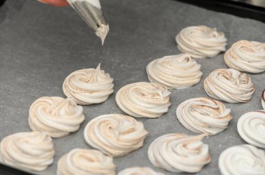 Zarif kremalı kurabiyeler parşömen kağıdına konuyor. Sıcak, davetkar bir mutfak ortamında..