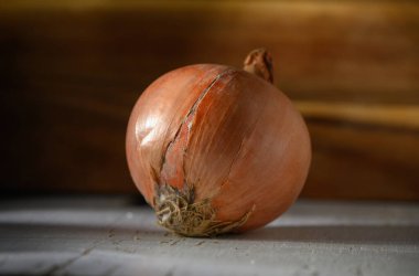 Portakallı bir soğan, sade ahşap bir masada oturur. Yumuşak bir şekilde aydınlatılır. Mutfağa sıcaklık ve cazibe katar..