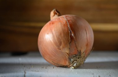 Çatlak bir soğanın yakın çekimi, dokulu derisini ve köklerini ortaya çıkarır. Doğal kusurlardaki güzelliği gözler önüne serer..