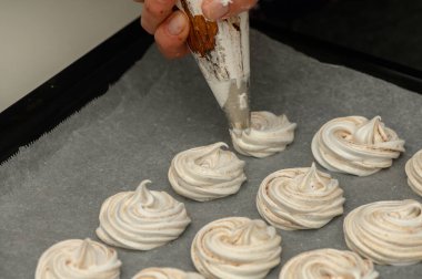 Becerikli bir fırıncı hassas kremalar şekillendirir, bir mutfak tepsisinde tatlı bir ikram için hazırlanır..