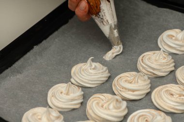 Zarif krema kıvrımları ustaca parşömen kâğıdına konur ve ustaca hazırlanmış bir pişirme tekniğini gösterir..