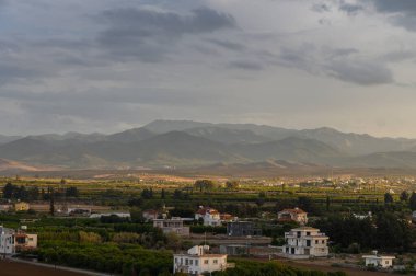 Alacakaranlık yaklaşırken görkemli dağlara doğru uzanan yeşillik tarlaları doğa açısından zengin sakin bir manzara çiziyor..