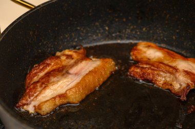 Altın pastırma dilimleri sıcak bir tavada kızarır ve sıcacık mutfak havasını zevkle dolduran lezzetli aromalar yayar..