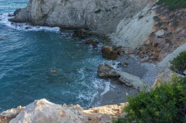 Güneş ufkun altına batıyor, sakin sulara ve engebeli uçurumlara ılık tonlarla vuruyor..