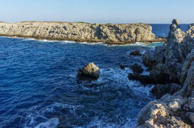 Engebeli kayalıkların sakin güzelliğini deneyin. Açık mavi bir gökyüzünün altında denizin yumuşak dalgalarıyla karşılaşın..