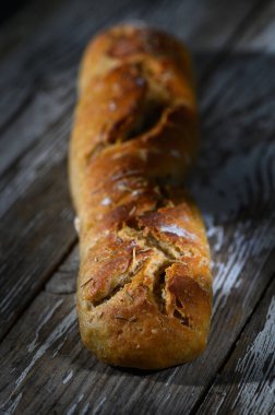 Freshly baked artisan bread rests on a wooden surface, showcasing its rich texture and inviting warmth. clipart