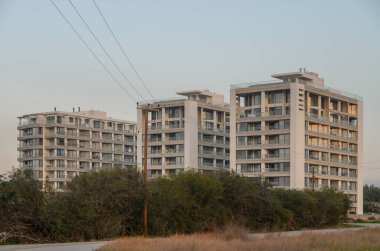 Yeşilliklerle çevrili ve yumuşak akşam ışığıyla yıkanmış yeni apartman daireleri çağdaş mimari sergileniyor..