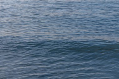 Yumuşak dalgalar, güneş batarken sakin sularda dalgalanır ve sahil kenarında sakin bir atmosfer yaratır..