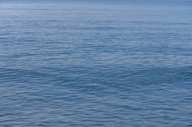 Açık mavi sular, gün ortası güneşinin altında sonsuz kadar uzanır. Huzur dolu bir manzara yaratır..