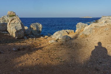 Sakin okyanusa doğru kayalık bir yol iniyor, akşam yaklaşırken dalgalar kıyıya vuruyor..