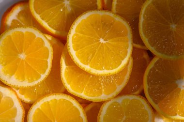 Sulu portakal dilimleri bir kâsede kesişiyor, canlı renklerini sergiliyorlar ve yazın tadını davet ediyorlar..