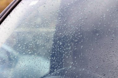 Yağmur damlaları bir arabanın camında toplanır ve yağmurlu bir günde sessiz şehir zemininde büyüleyici bir desen oluşturur..