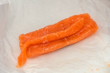 Parşömen kağıdının üzerine uzanmış parlak portakallı somon filetoları baharat ve lezzetli bir yemek için hazırlanmayı bekliyor..