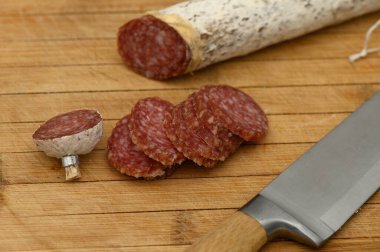 Pişmiş et dilimleri, sıcak ahşap bir yüzeyde bıçakla zarif bir şekilde düzenlenir..