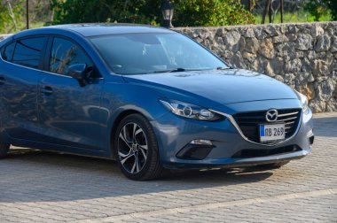 Gaziveren Kıbrıs Rum Kesimi 16.01.2025 Şık bir araba taş bir duvarın yakınındaki kaldırım taşları üzerinde dinleniyor, huzurlu bir günün güneşinin altında güneşleniyor.