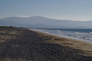 Sakin bir sahil boyunca uzanan altın kumlar yumuşak dalgaların sisli bir alacakaranlık gökyüzünün altında kumsalı okşaması gibi..