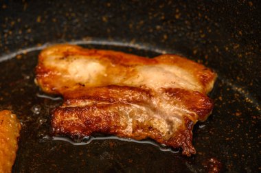 Sıcak tavada sulu domuz eti parçaları karamelize ederek pişirme işlemi sırasında lezzetli aromalar yayıyor..