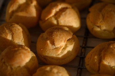 Sıcak hamur işleri serinletici bir rafta oturur, kabuklu üstleri hoş bir mutfağın yumuşak ışığında parlar..