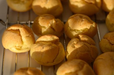 Taze pişmiş altın hamur işleri serinletici bir rafta dinleniyor, sıcacık bir mutfak alanında güneşin altında güneşleniyor..