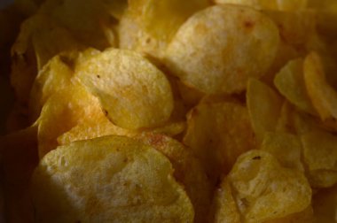 Close-up view of beautifully fried potato chips gleaming under soft golden light, tempting for a delightful crunch clipart