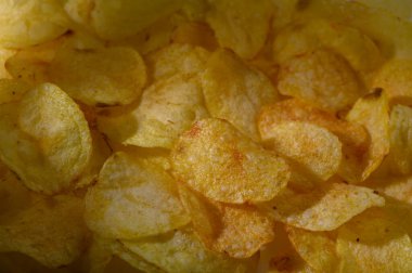 Altın patates cipsleri hafif ışığın altında parıldıyor, dostça atıştırmalıklarla dolu bir anda çıtırdıyor.