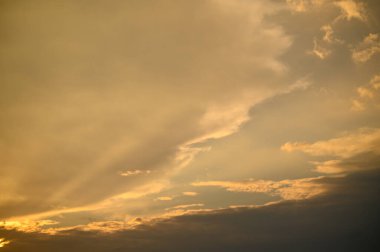 Sıcak altın ve turuncu renkler bulutları aydınlatır. Güneş, huzur dolu topraklarda yavaşça batar..