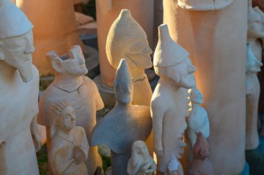 Craftsmen display clay figures bathed in warm sunset light, showcasing the essence of artistry. clipart