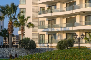 Şık binalar yemyeşil bahçelerin ve palmiye ağaçlarının yanında yükseliyor, doğayı günbatımında çağdaş tasarım ile mükemmel bir şekilde harmanlıyor..