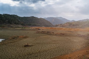 A vast expanse of dry, cracked earth stretches under a cloudy sky, revealing the effects of severe drought in nature. clipart