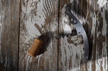 Parlak bir tirbuşon ve mantar kırsal bir ahşap masanın üzerinde uzanır. Nazik güneş ışığıyla aydınlatılır..