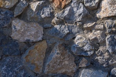 Güneş ışığı, yıpranmış taş bir duvarın zengin dokularını ve renklerini ortaya çıkararak doğanın mimari sanatını gözler önüne seriyor..
