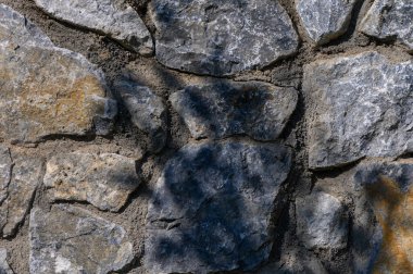 Sunlight spills across the rough stones, showcasing the intricate textures and tranquil beauty of this natural wall. clipart