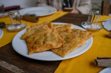 Beyaz bir tabağa yerleştirilmiş gevrek, altın sarısı hamur işleri. Arkadaşlarıyla kırsal bir akşam yemeğine davet ediyorlar..