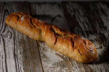 Güzel bir kır ekmeği zarif bir şekilde ahşap bir yüzeyde oturuyor, narin bir ışıkta parlıyor, herkesi davet ediyor..