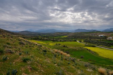 Bulutlu gökyüzünün altında yuvarlanan yeşil tepeler huzuru ve doğayla bağlantıyı davet eder..