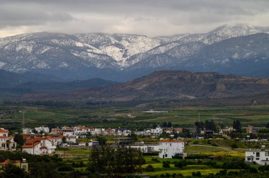Karla kaplı tepeler, yemyeşil yemyeşil çayırları ufka doğru uzanan tuhaf bir köyün üzerinde..
