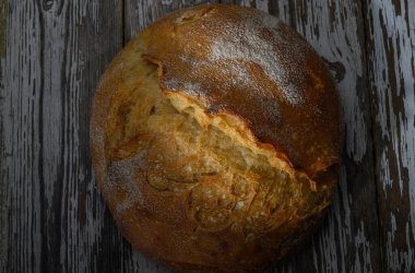 Dışı çıtır çıtır olan altın kahverengimsi ekmek, yıpranmış ahşabın üzerinde oturur ve ev yapımı yemekleri davet eder..