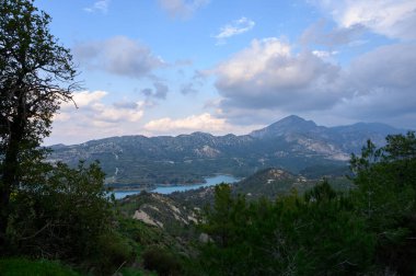Bereketli yeşil bir göl sarar Alacakaranlık gökyüzünü yansıtan, uzak dağlar manzaraya derinlik katar.