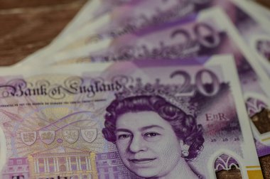 İngiltere 'nin zarif yirmi poundluk banknotları ahşap bir masanın üzerinde ayrıntılı tasarımları ve canlı renkleri gözler önüne seriyor..