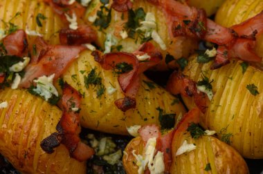 Çıtır domuz pastırması ve taze otlarla süslenmiş lezzetli altın patatesler ağız sulandırıcı bir yemek hazırlıyor..