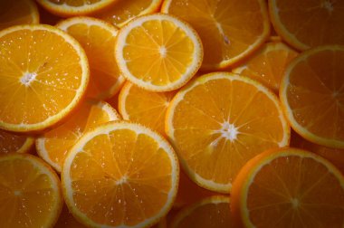 Güneş ışığı parlak portakal dilimlerinin arasından süzülür, sulu kısımlarını kırsal bir masada sergiler..