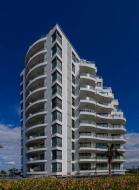 Çarpıcı bir modern yapı, açık gökyüzüne karşı duran kalın çizgiler ve geniş balkonlara sahiptir..