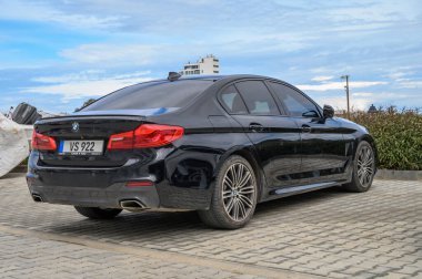 Gaziveren Kıbrıs Rum Kesimi -28.02.2025 Modern lüks bir araba asfalt bir alanda duruyor, zarif tasarımı ve parlak dış görünüşü doğaya karşı sergileniyor.