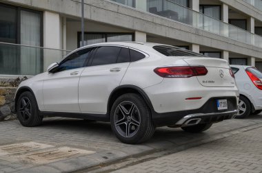 Gaziveren Kıbrıs Rum Kesimi -28.02.2025 Modern bir binanın yanında lüks lüks lüks bir SUV parkı, bulutlu bir günde kentsel zarafet sergiliyor.