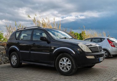 Gaziveren Kıbrıs Rum Kesimi -28.02.2025 Parlak siyah bir SUV gümüş renkli kompakt bir arabanın yanında duruyor..