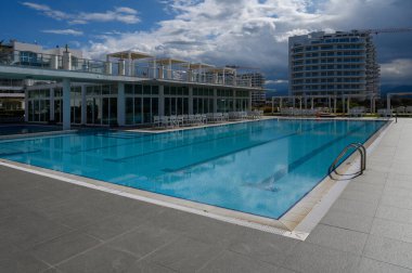 Ziyaretçilerin modern ortamdaki dingin havuz atmosferinin tadını çıkardıkları sakin suda yansımalar dans ediyor..