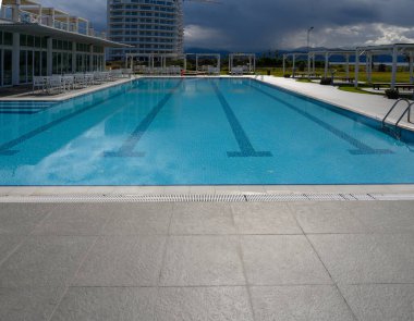 Ferahlatıcı sular çağdaş bir tatil köyünde parıldıyor. Arkaplan bulutlara ve uzak dağlara vuruyor..